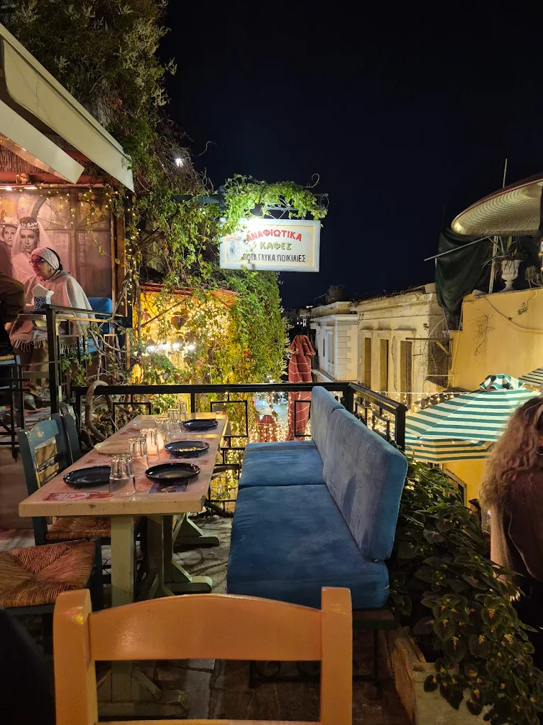 The candle-lit night terrace at Anafiotika with a blue velvet sofa and strings of warm light